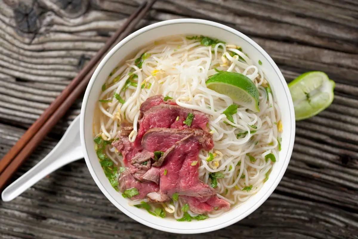 A bowl of pho, complete with rice noodles, protein, and other toppings.